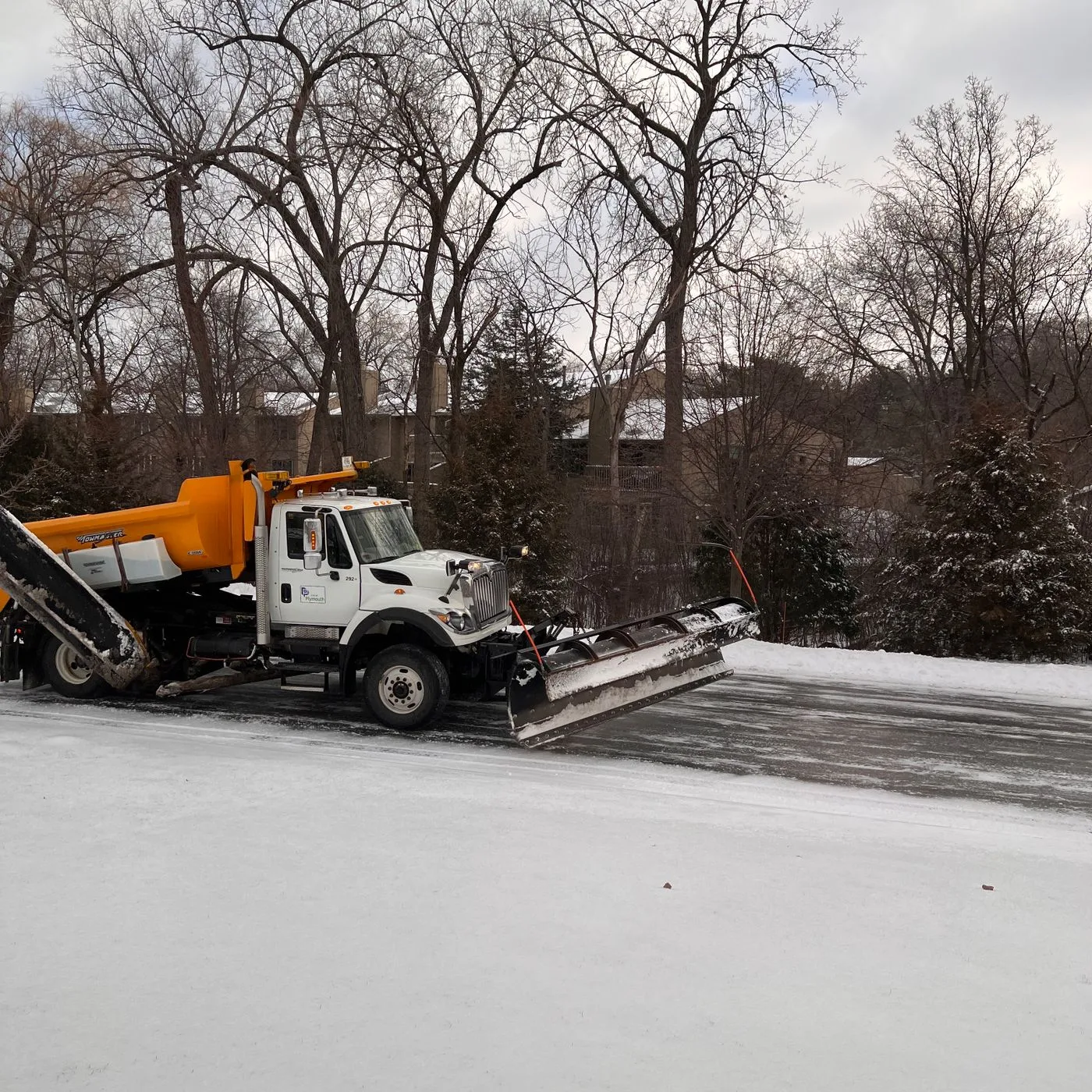 Truck with a snow plow clearing a driveway during a Central Indiana winter